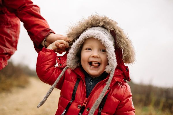 Laughing child bundled in a red winter coat outdoors