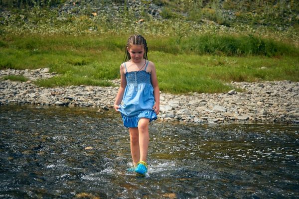 Girl wading in a shallow creek on a summer day