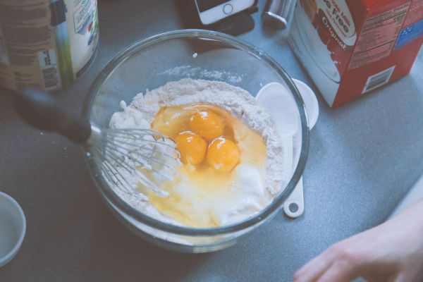 Mixing pancake batter with flour and eggs in a glass bowl