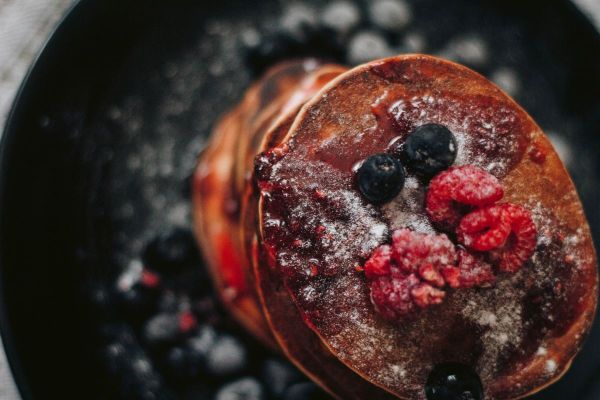 Stack of fluffy pancakes topped with fresh berries and powdered sugar