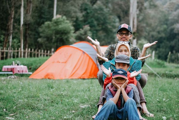 A happy family camping beside a bright orange tent