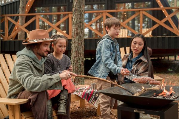 A family roasting marshmallows outside a cabin