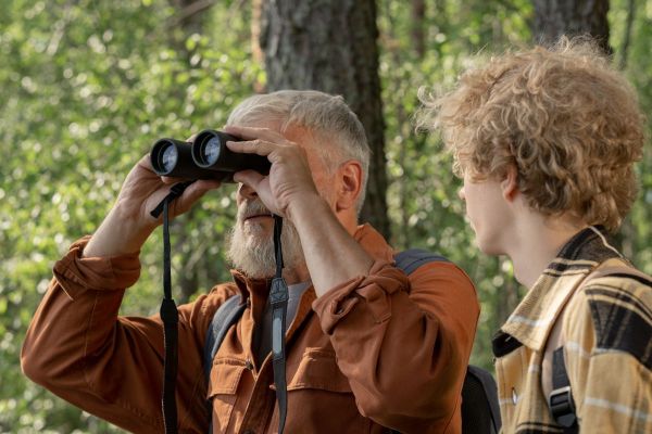 Grandpa looking through binoculars on a forest walk