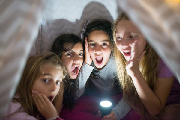 Kids with a flashlight at a sleepover in a tent